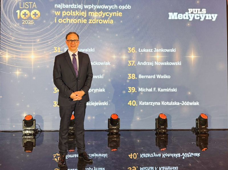 Profesor Andrzej nowakowski na tle niebieskiego baneru z listą 100 najbardziej wpływowych osób w polskiej medycynie i ochronie zdrowia
