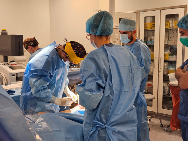 Zespół lekarzy w trakcie operacji z widoczną salą operacujną